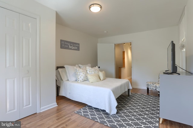 bedroom with baseboards, wood finished floors, and a closet