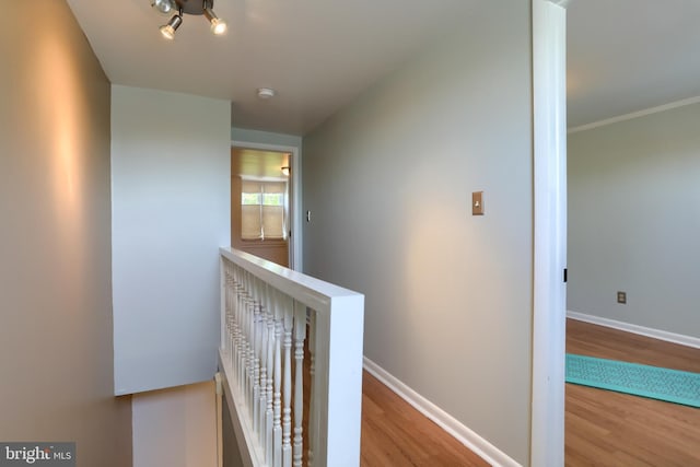 corridor with baseboards, an upstairs landing, and wood finished floors