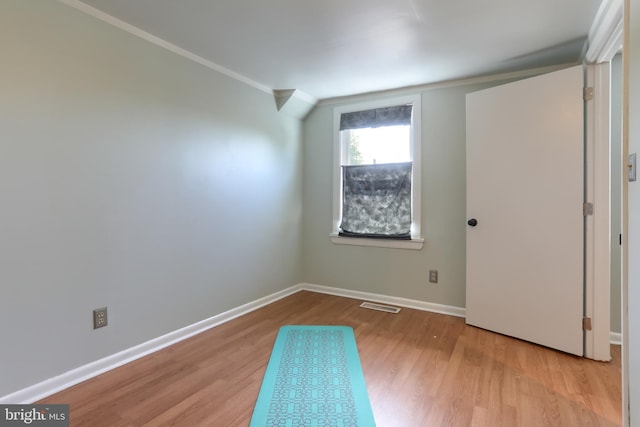 unfurnished room featuring visible vents, baseboards, crown molding, and wood finished floors