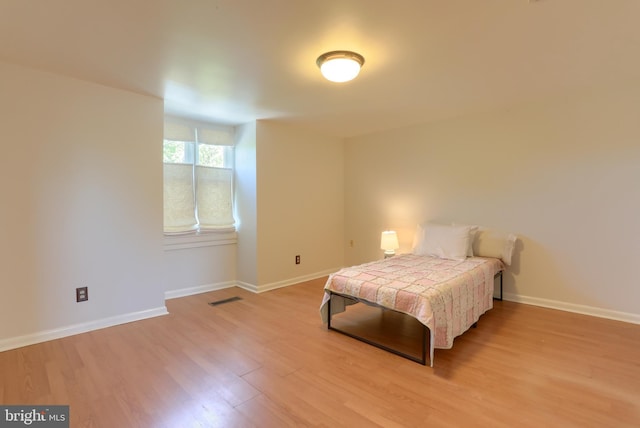 bedroom featuring baseboards, visible vents, and light wood finished floors