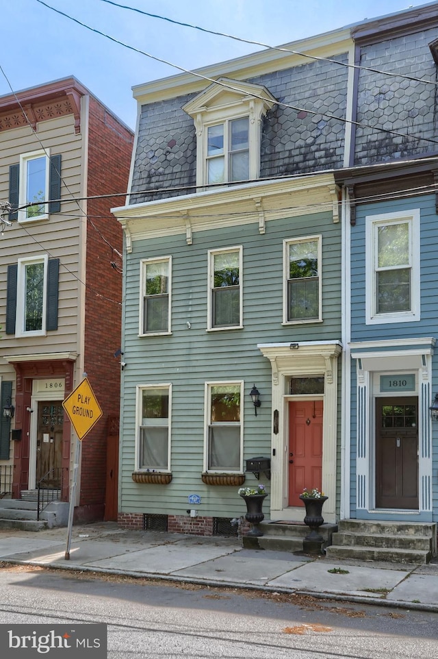 view of front of home featuring mansard roof, a high end roof, and entry steps