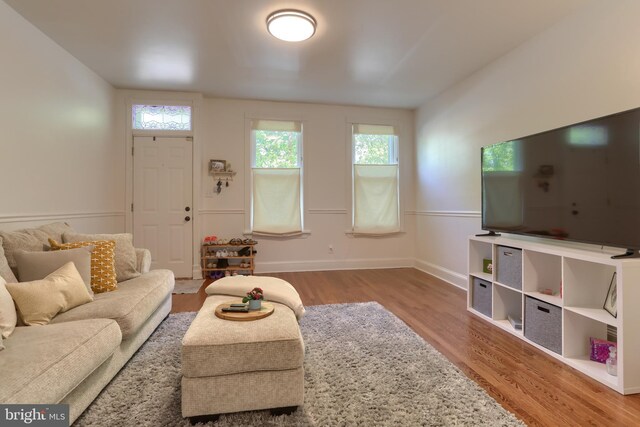 living area with baseboards, plenty of natural light, and wood finished floors