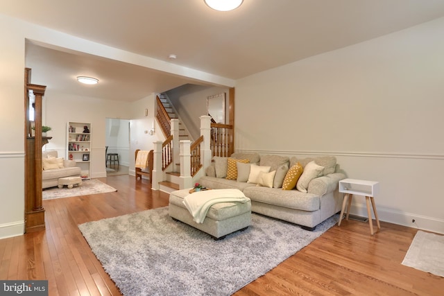 living room with baseboards, wood finished floors, and stairway