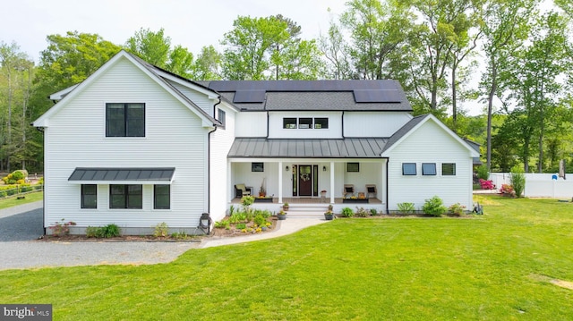 32991 Daisey Rd, Frankford, DE 19945 - view of front of house featuring a front lawn, fence, covered porch, a standing seam roof, and roof mounted solar panels