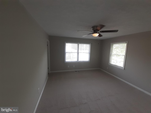 carpeted spare room featuring baseboards and ceiling fan