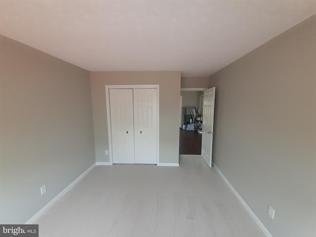 unfurnished bedroom featuring baseboards, light carpet, and a closet