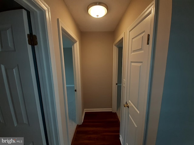 hallway featuring baseboards and dark wood finished floors