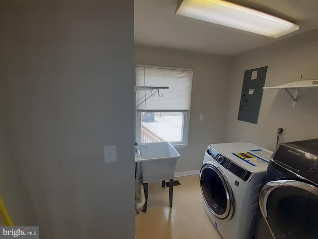 laundry area with laundry area, washer and dryer, baseboards, electric panel, and a sink