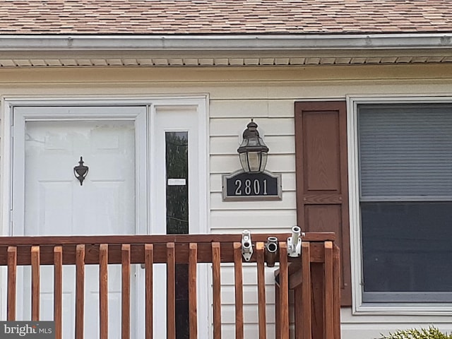 doorway to property featuring roof with shingles