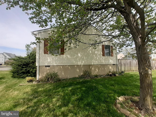view of side of property with fence, a yard, and crawl space