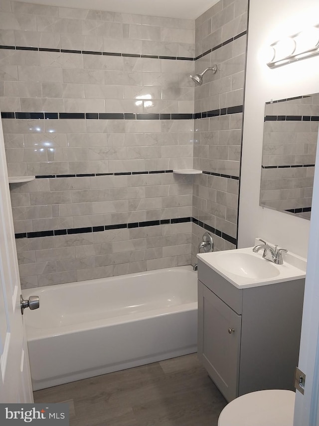 full bath with toilet, washtub / shower combination, wood finished floors, and vanity