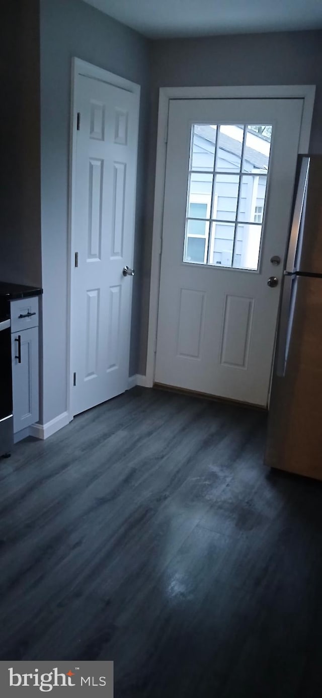 doorway to outside featuring baseboards and dark wood finished floors