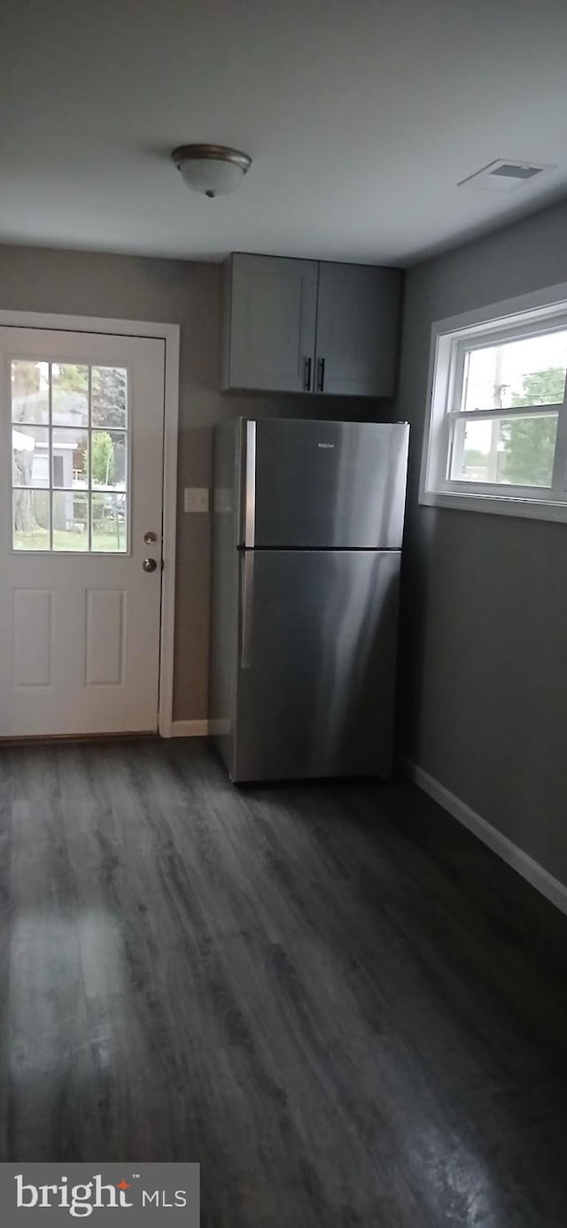 unfurnished dining area featuring baseboards, dark wood finished floors, and visible vents