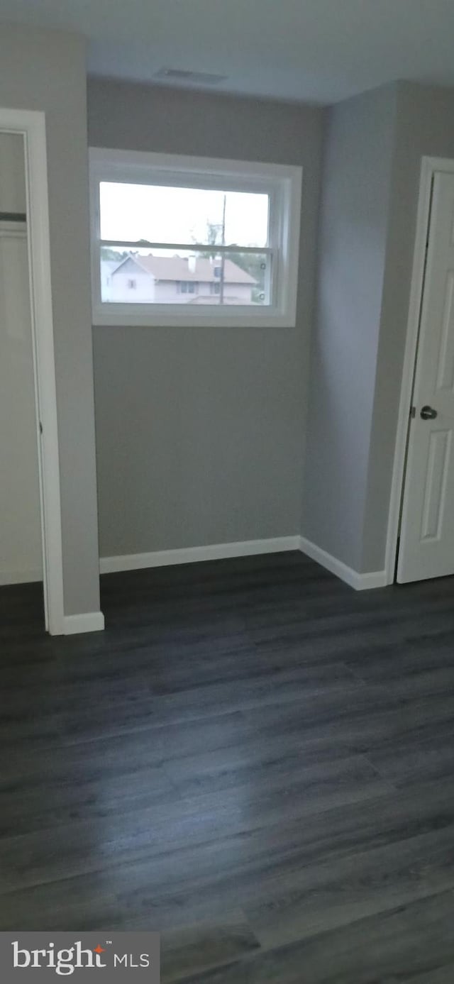 unfurnished bedroom with baseboards and dark wood-style floors
