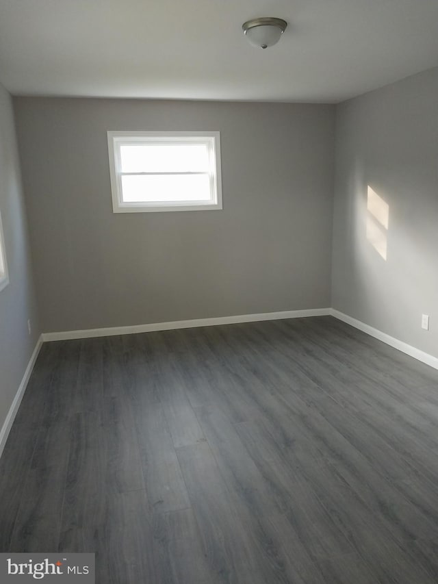 unfurnished room featuring baseboards and dark wood-style flooring