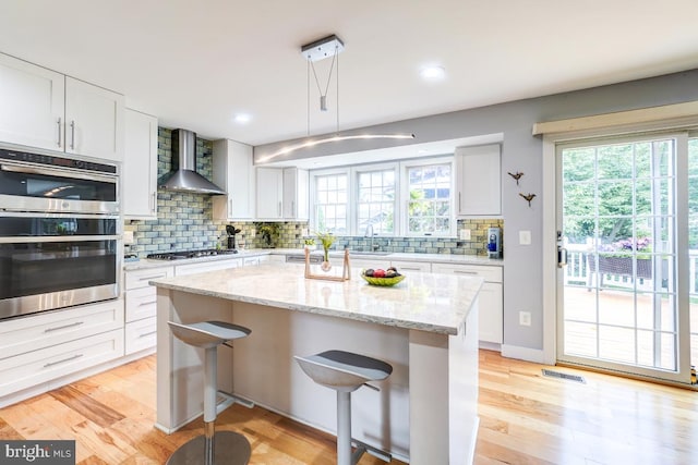 20662 Ashleaf Ct, Sterling, VA 20165 - kitchen featuring wall chimney exhaust hood, appliances with stainless steel finishes, tasteful backsplash, a kitchen breakfast bar, and white cabinets