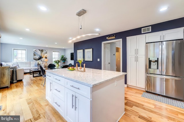 20662 Ashleaf Ct, Sterling, VA 20165 - kitchen with stainless steel fridge, white cabinets, light stone countertops, a kitchen island, and decorative light fixtures