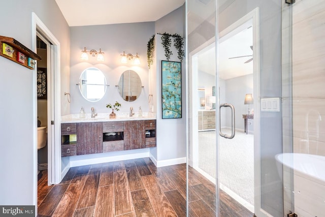 20662 Ashleaf Ct, Sterling, VA 20165 - bathroom featuring toilet, wood finished floors, a shower stall, double vanity, and a ceiling fan