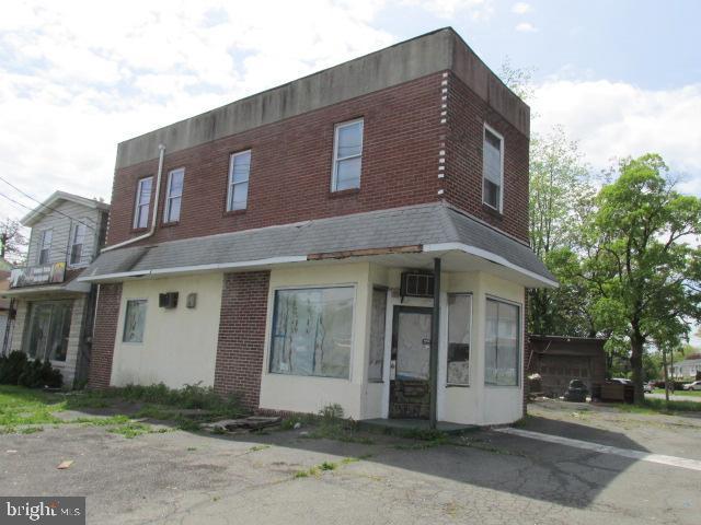 view of front of house featuring brick siding and a wall unit AC