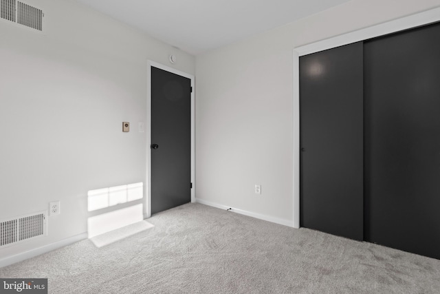 unfurnished bedroom with carpet floors, baseboards, visible vents, and a closet