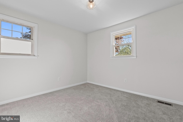 empty room featuring visible vents, carpet, baseboards, and a healthy amount of sunlight
