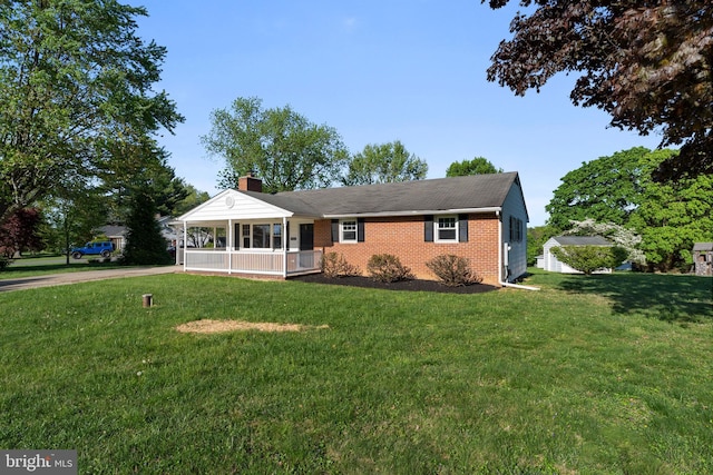 ranch-style house featuring a front yard, a chimney, brick siding, concrete driveway, and a porch