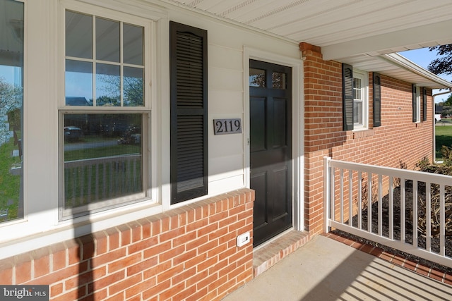 property entrance featuring covered porch and brick siding