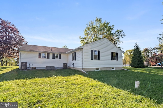 rear view of house featuring central AC unit and a yard