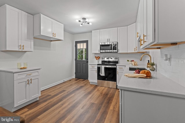 kitchen with a sink, white cabinets, tasteful backsplash, and stainless steel appliances