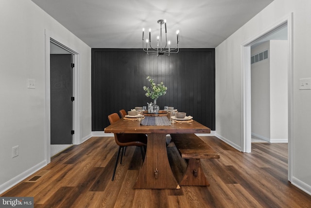 dining area featuring baseboards, a chandelier, wood finished floors, and visible vents