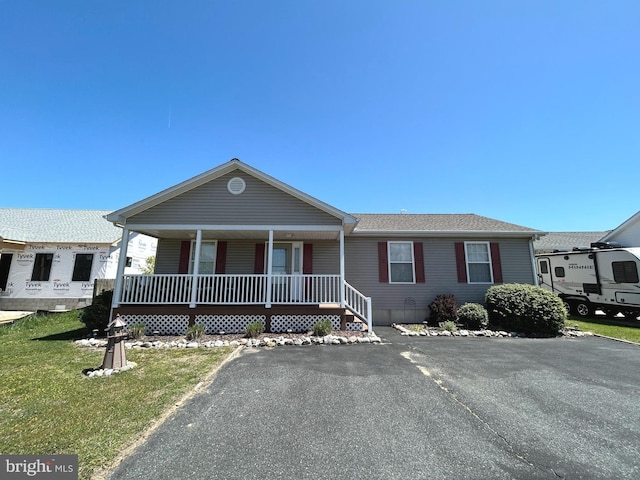 ranch-style house with a shingled roof, a porch, and a front yard