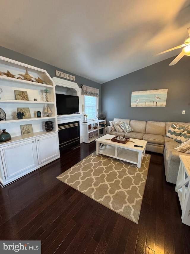 living room featuring dark wood-type flooring, a ceiling fan, and vaulted ceiling