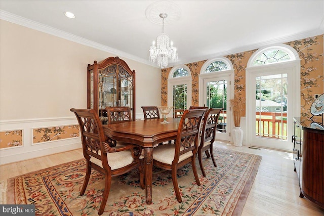 dining area featuring an inviting chandelier, baseboards, crown molding, and light wood-style flooring
