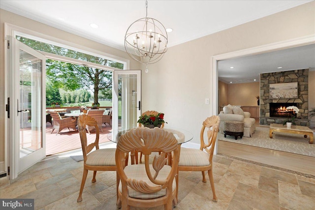 dining space featuring stone finish floor, crown molding, a fireplace, a chandelier, and recessed lighting