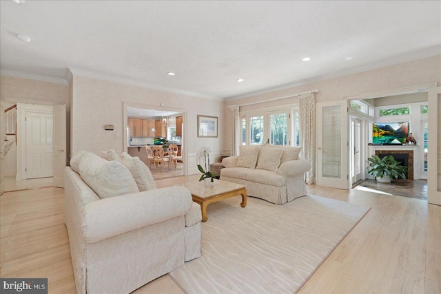 living area featuring recessed lighting, ornamental molding, a fireplace, and light wood finished floors