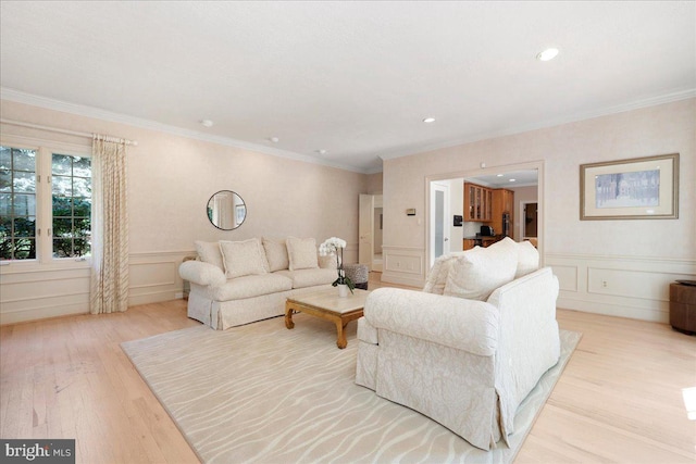 living area featuring crown molding, wainscoting, a decorative wall, and light wood-style flooring
