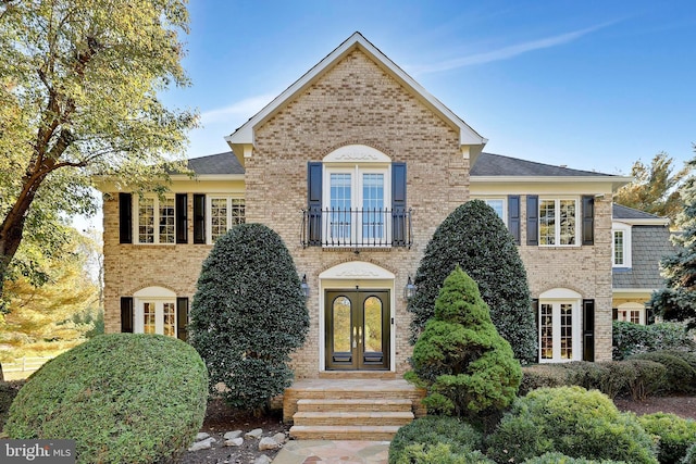 view of front of property featuring french doors, a shingled roof, and brick siding