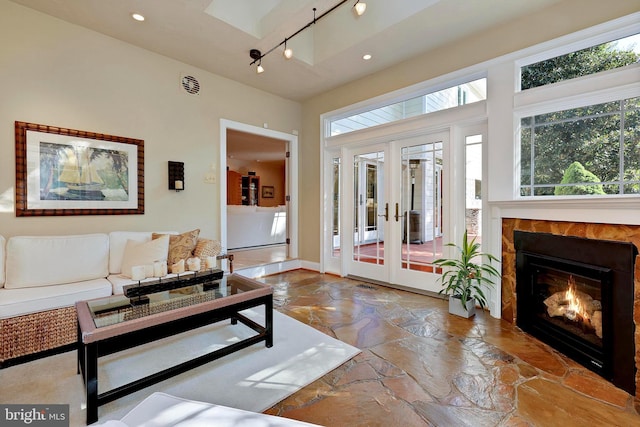 living area featuring french doors, stone floors, visible vents, and a healthy amount of sunlight