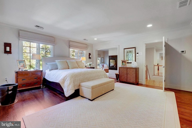 bedroom with crown molding, recessed lighting, wood finished floors, and visible vents