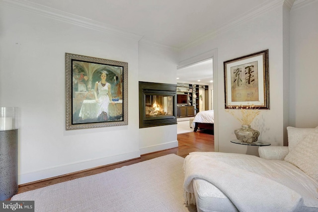 bedroom with crown molding, a multi sided fireplace, baseboards, and wood finished floors