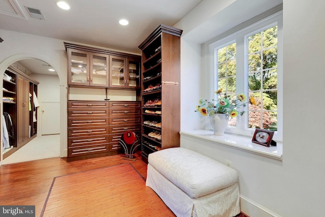 walk in closet with arched walkways, visible vents, and wood finished floors