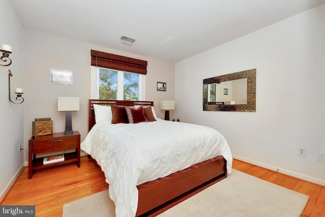 bedroom featuring baseboards, wood finished floors, and visible vents