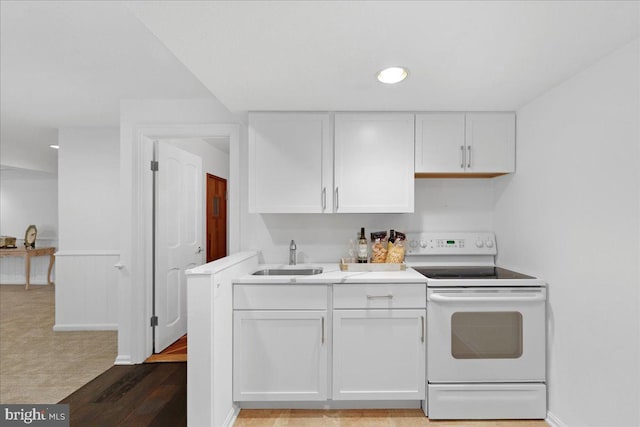 kitchen featuring a sink, electric range, white cabinets, and light countertops