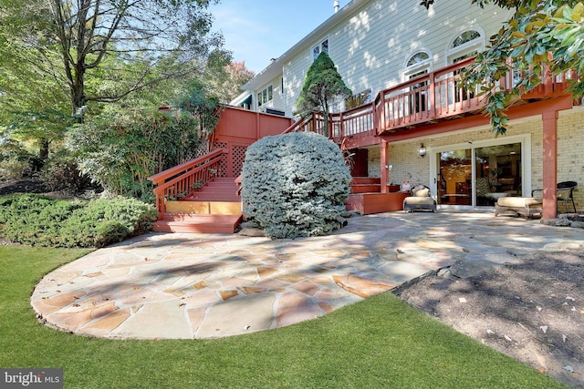 back of house featuring a deck, a patio area, stairway, and brick siding