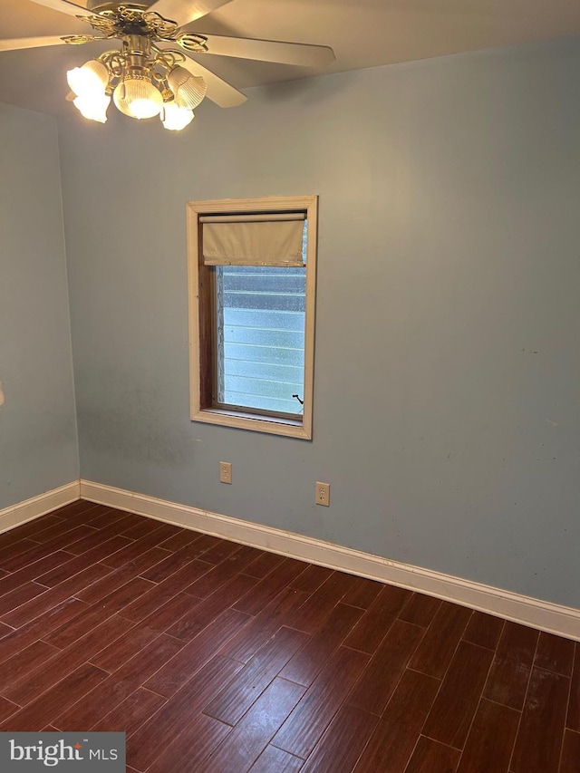 empty room featuring dark wood finished floors, ceiling fan, and baseboards