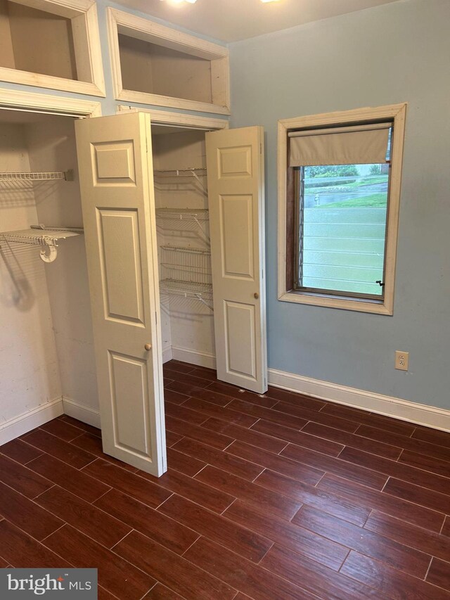 unfurnished bedroom with dark wood-style floors and baseboards