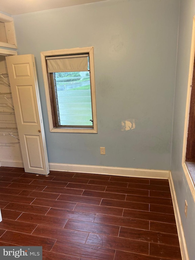 empty room featuring dark wood-style flooring and baseboards