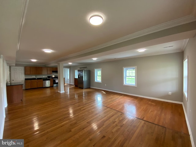 unfurnished living room with crown molding, baseboards, and dark wood finished floors