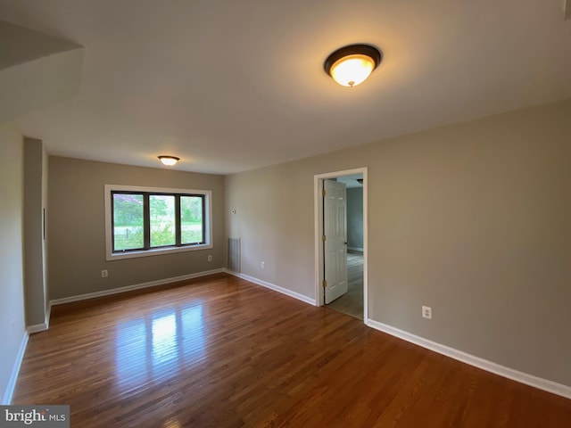 spare room featuring baseboards and dark wood finished floors