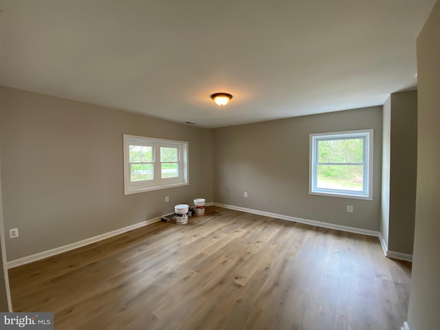 spare room with baseboards and wood finished floors